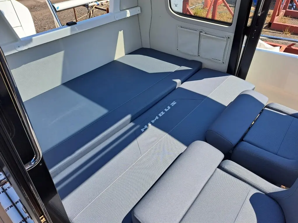 Interior of a boat showcasing grey seating cushions with the word "Nimbus" on the largest cushion, under natural sunlight.